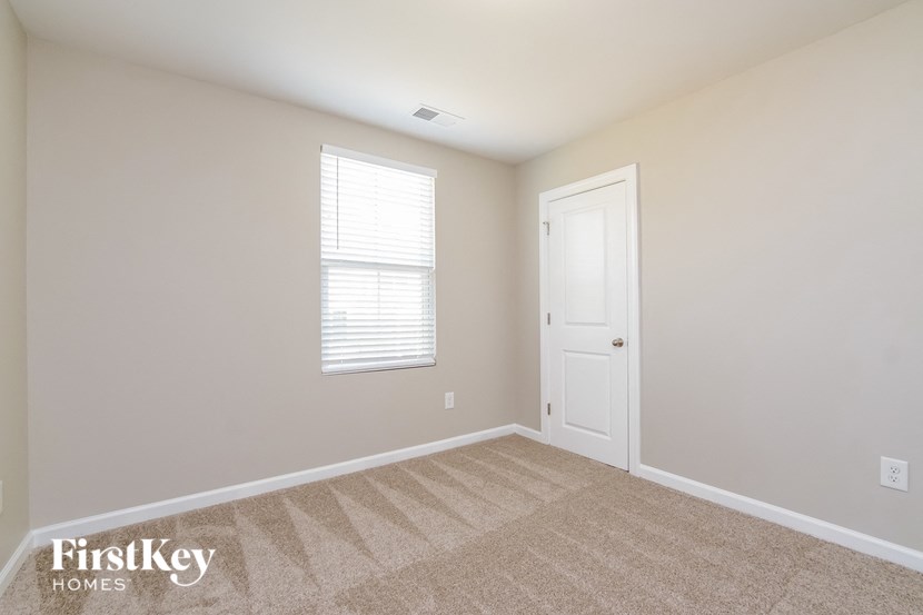 a bedroom with a door and a window and a carpeted floor