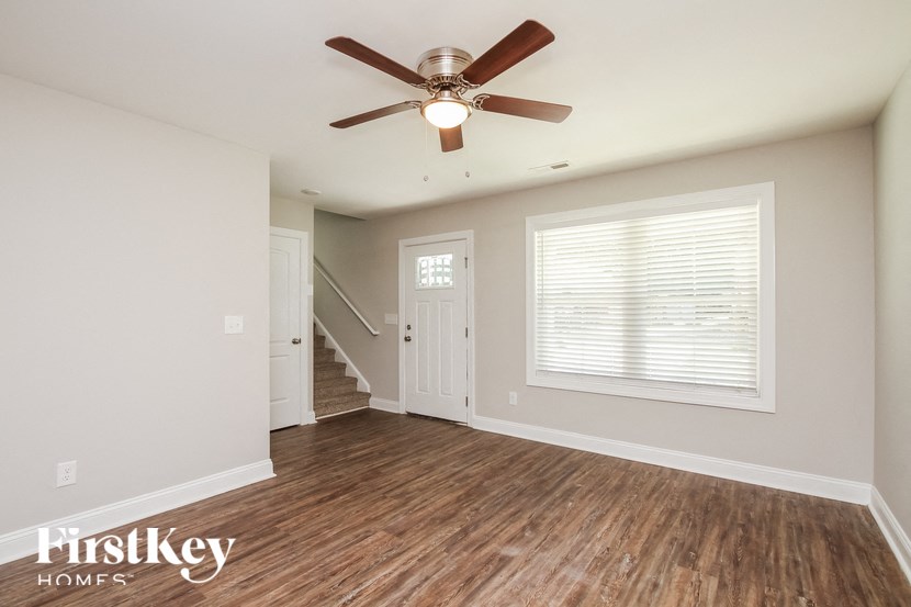 A room with a ceiling fan and wooden flooring.