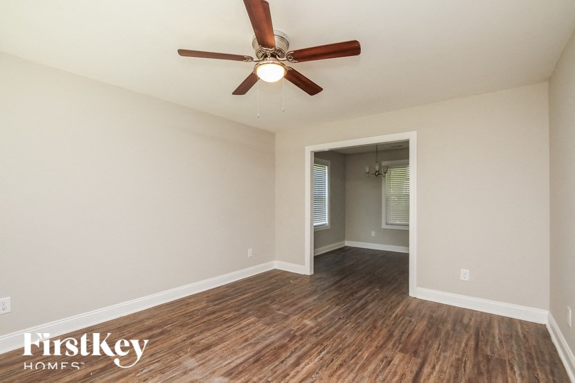 A room with a ceiling fan and wooden flooring.