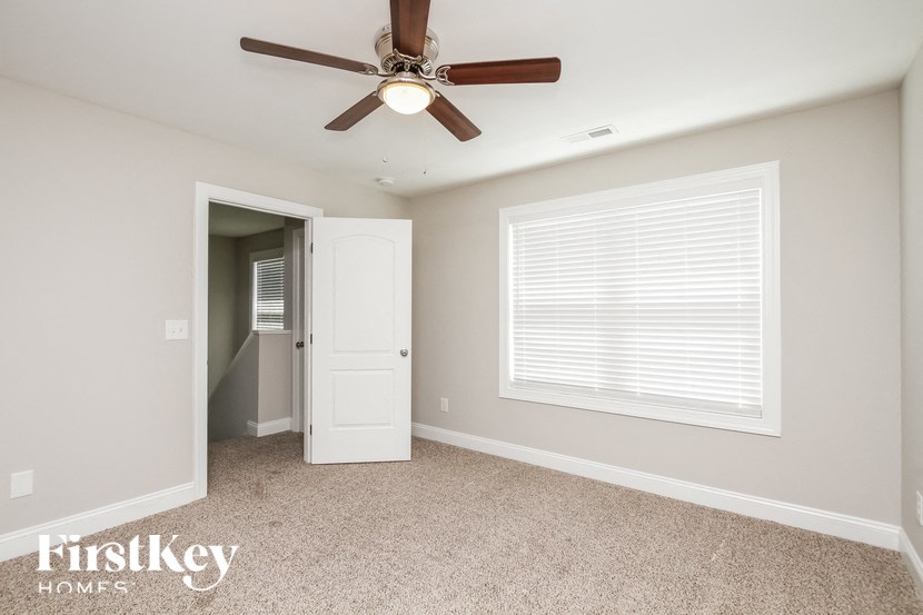 A room with a fan and a door leading to another room.