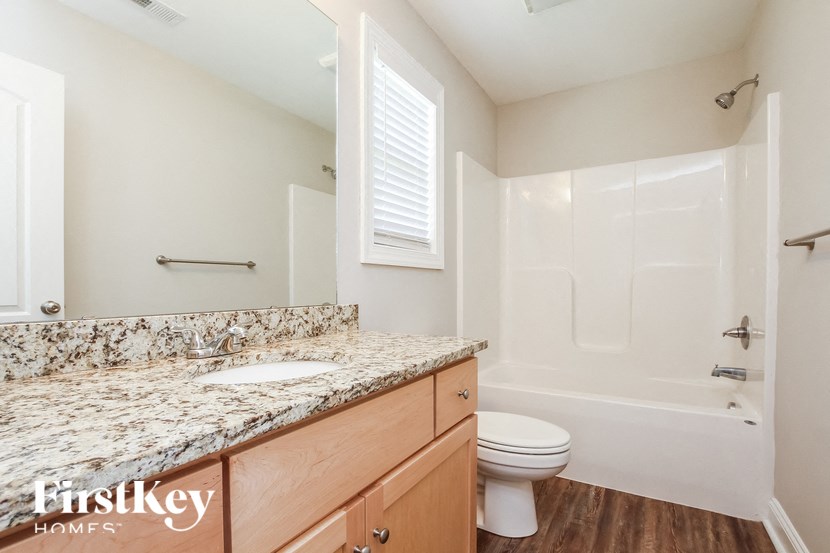 A bathroom with a marble countertop and a toilet.