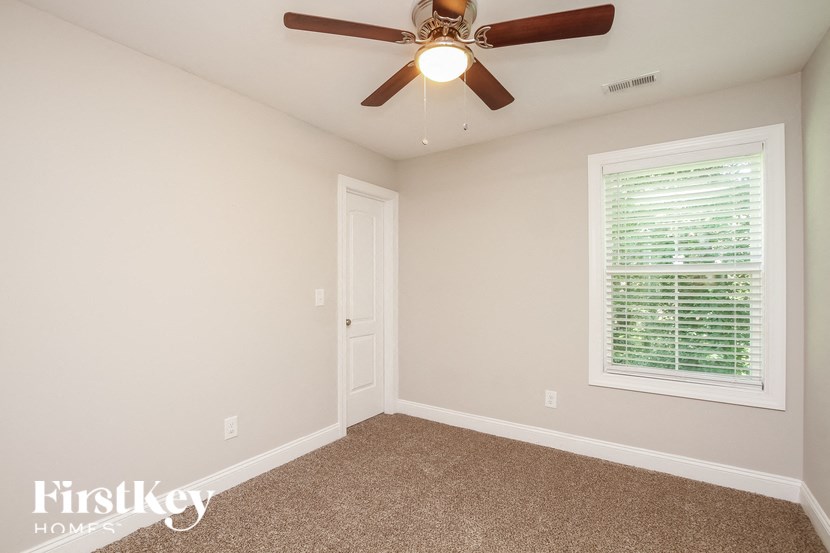 A room with a ceiling fan and a window with blinds.