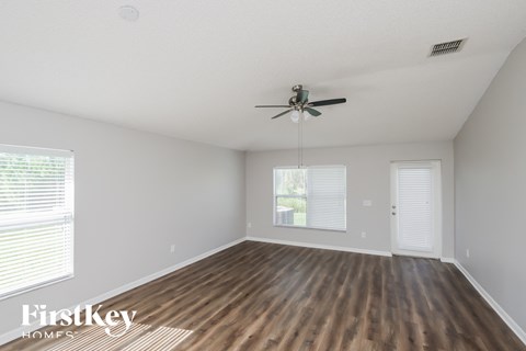 the spacious living room with hardwood floors and a ceiling fan