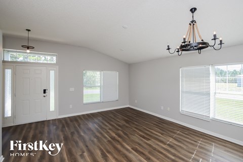 an empty living room with a chandelier and windows