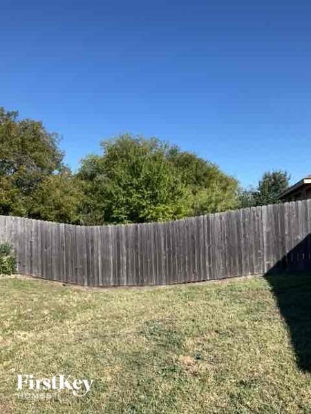 A wooden fence encloses a grassy yard.