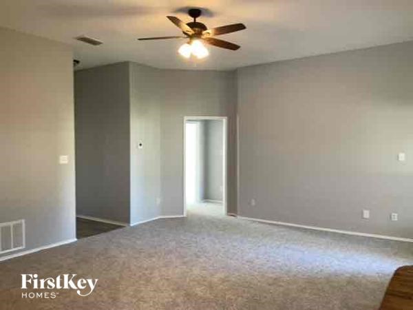 A room with a ceiling fan and a doorway leading to another room.