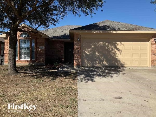 A house with a garage door and a tree in front.