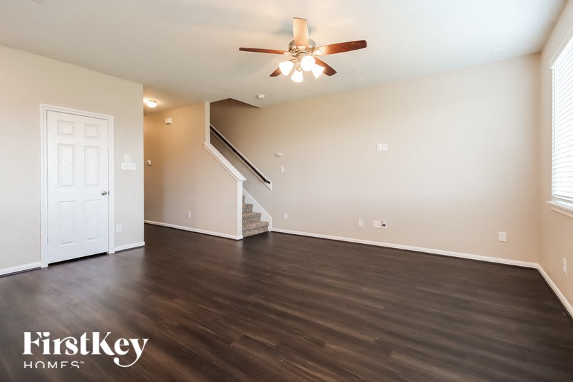 A spacious room with a staircase and a ceiling fan.
