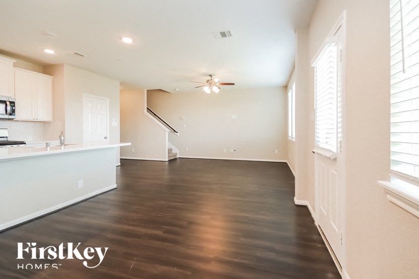 A spacious kitchen and living room with wooden floors and white walls.