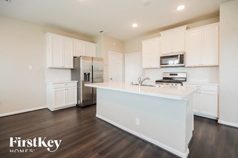 A kitchen with white cabinets and a wooden floor.