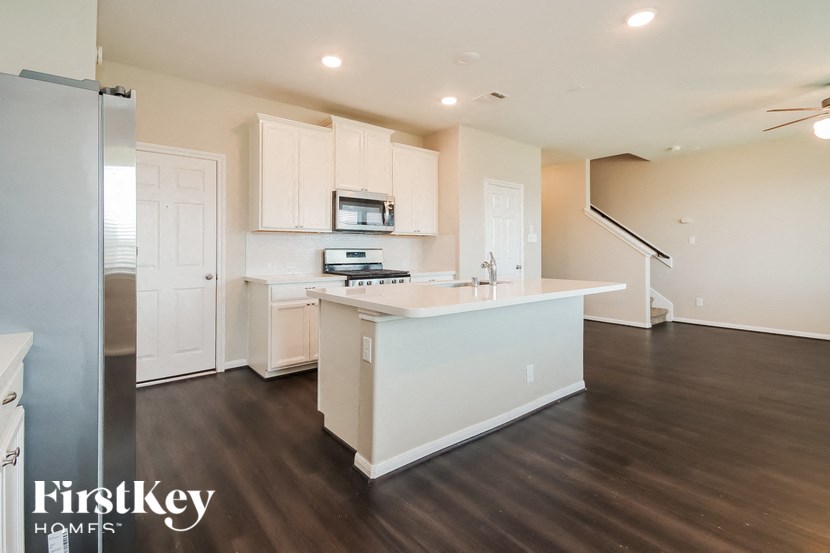 A kitchen with white cabinets and a white island with a microwave on top.