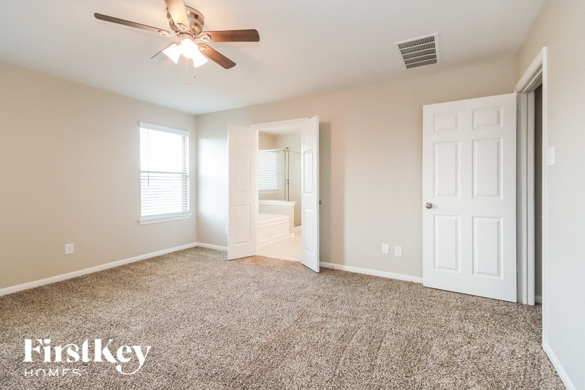A spacious room with a ceiling fan and carpeted floor.