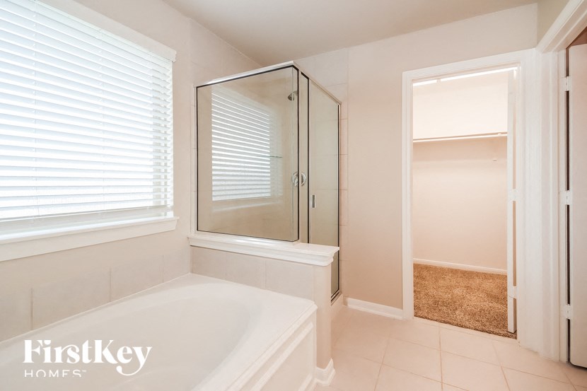 A white bathroom with a tub and a walk in shower.