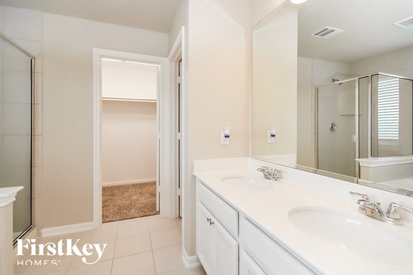 A bathroom with a sink, mirror, and a shower.