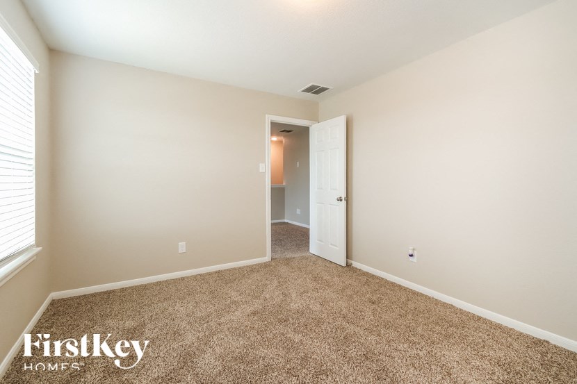 A carpeted room with a doorway leading to another room.