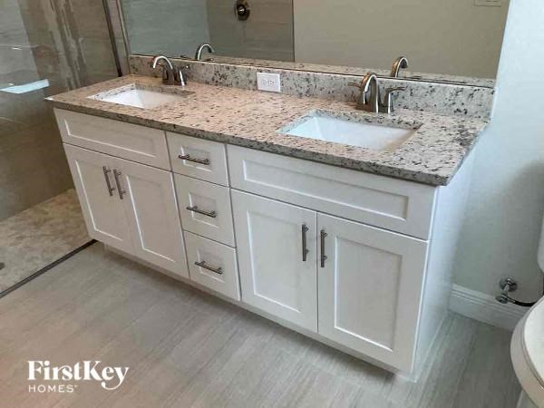 A bathroom with a granite countertop and white cabinets.