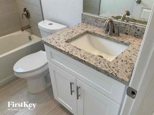 A bathroom with a granite countertop and white fixtures.