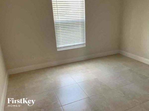 A room with a tiled floor and a window with blinds.