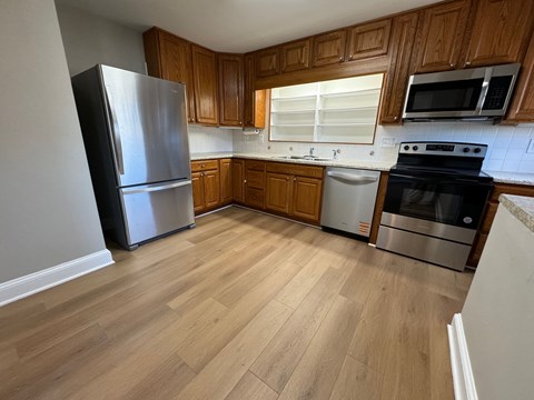 A kitchen with wooden cabinets and a stainless steel refrigerator.