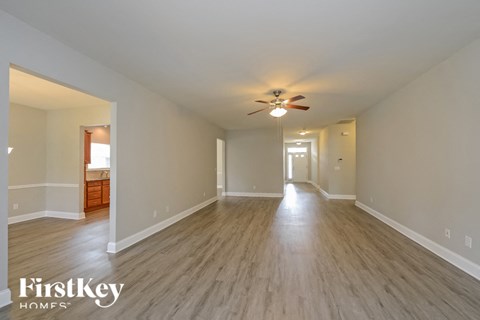 an empty living room with a ceiling fan and wood flooring