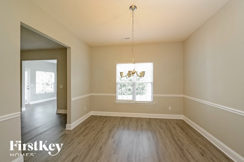 an empty dining room with wood floors and a window