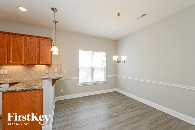 an empty kitchen and dining room with wood flooring and white walls