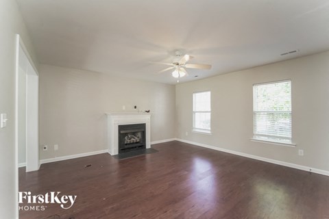 A spacious living room with a fireplace and a ceiling fan.