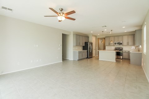 an empty living room and kitchen with a ceiling fan