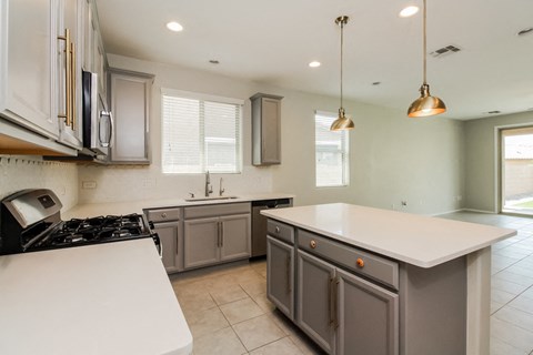 an updated kitchen with white counter tops and gray cabinets