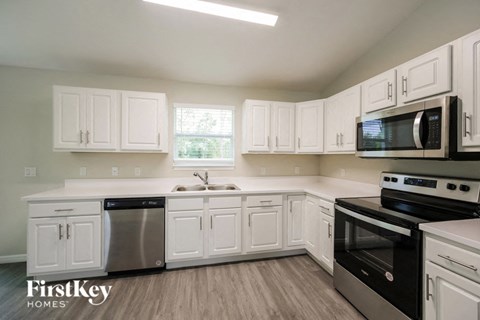 a kitchen with white cabinets and black appliances