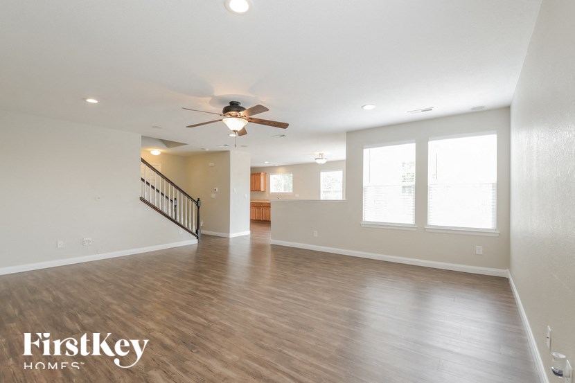 A spacious room with a staircase and a ceiling fan.