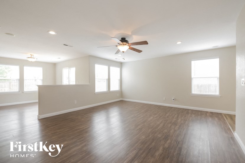A spacious room with wooden floors and a ceiling fan.