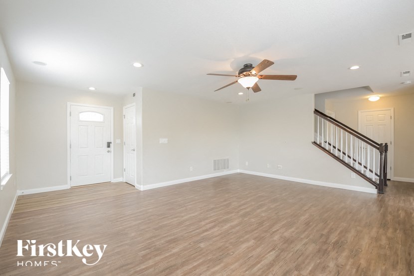 A spacious room with a wooden floor and a ceiling fan.