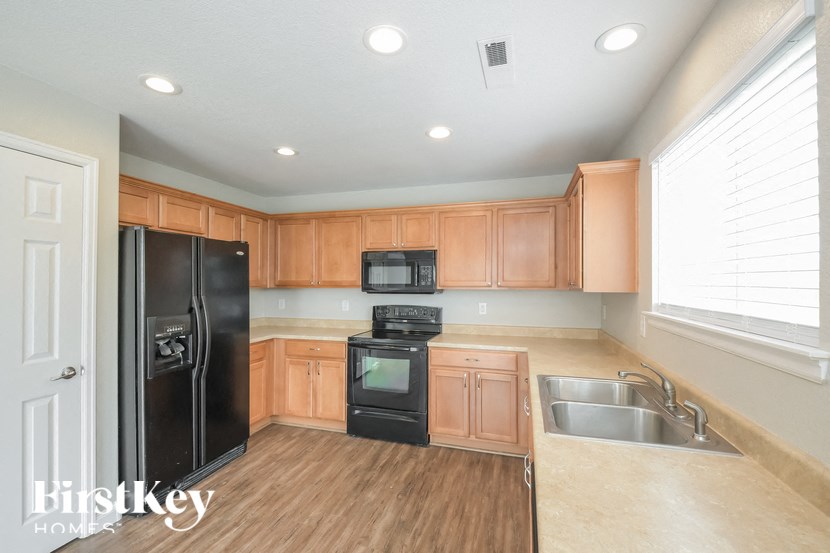 A kitchen with wooden cabinets and black appliances.