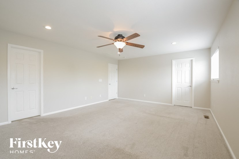 A spacious room with a ceiling fan and carpeted floor.