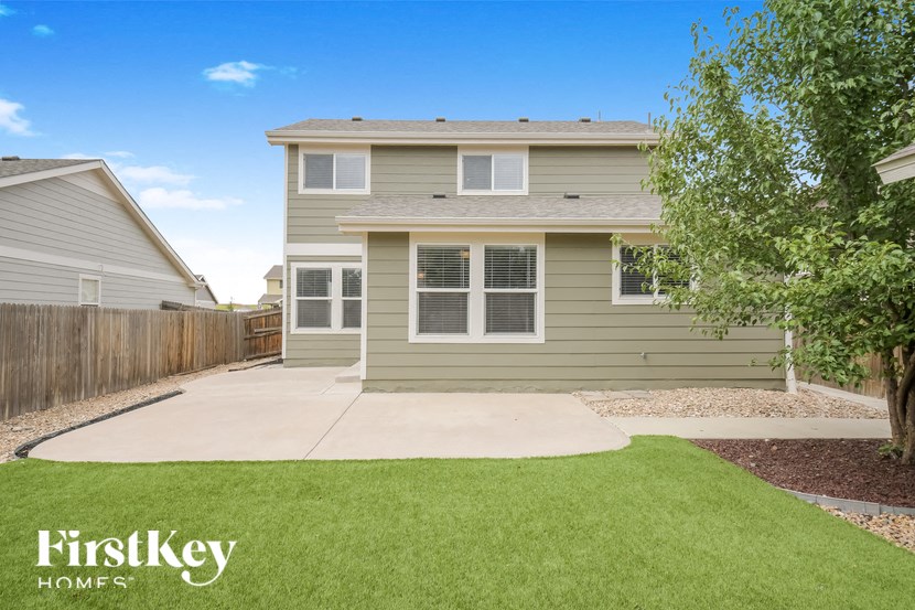 A house with a green lawn and a tree in front of it.