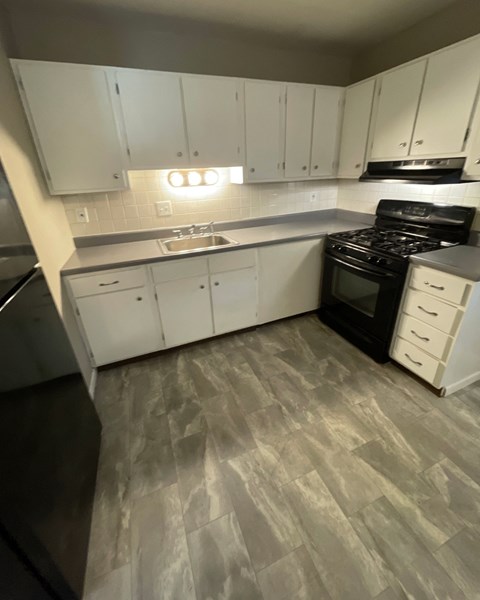 a kitchen with white cabinets and a stove and a sink