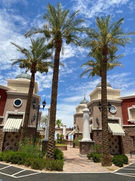 Palm trees in front of a building with a clock on the side.