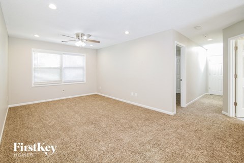 a spacious living room with carpet and a ceiling fan