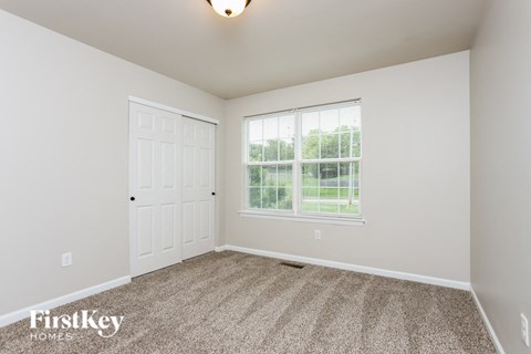 a bedroom with carpet and a white door and window