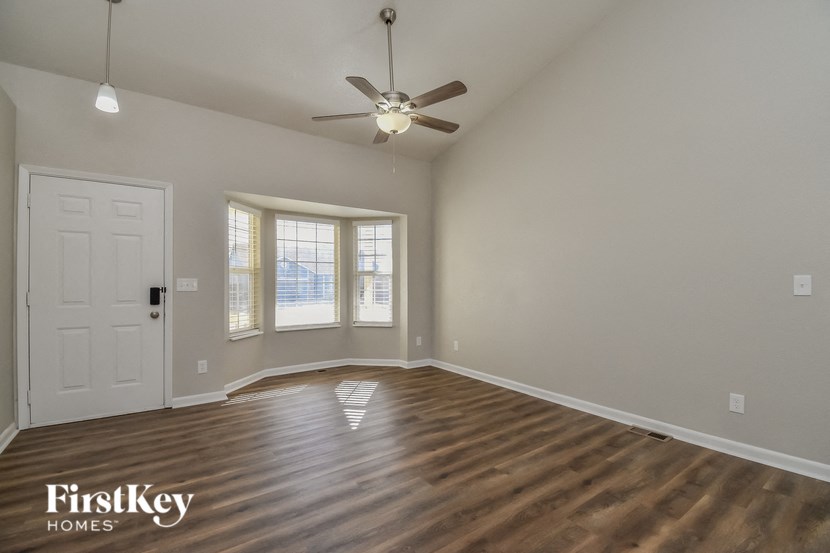the spacious living room with hardwood flooring and a ceiling fan