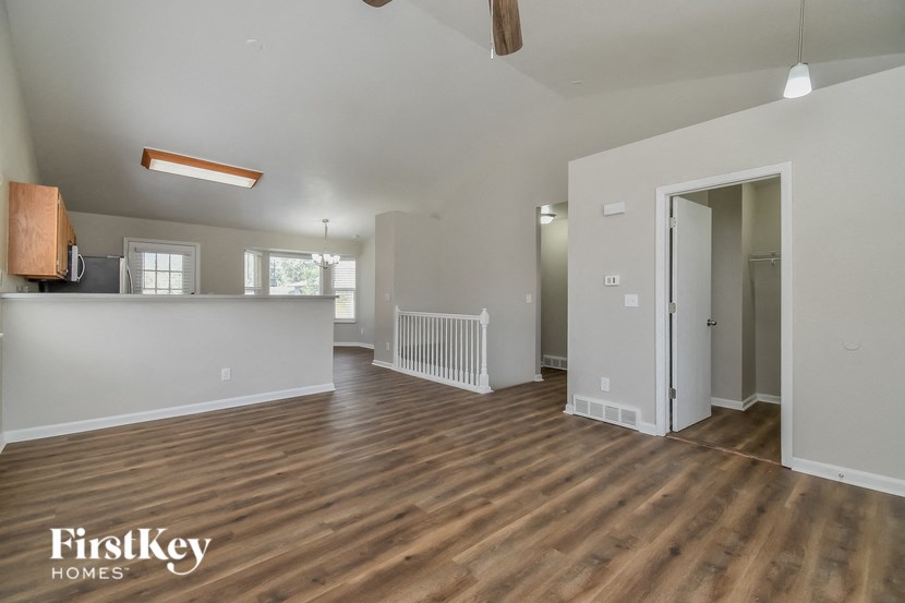 the living room and kitchen of an empty house with wood flooring
