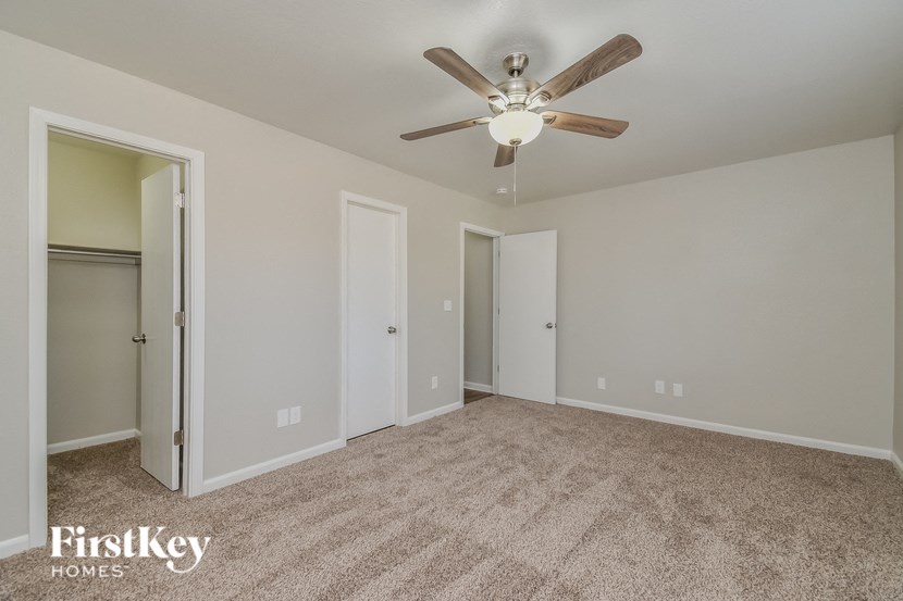 a empty living room with a ceiling fan and a closet