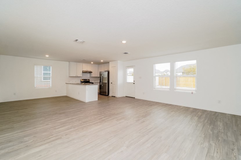 the living room and kitchen of an empty house with wood flooring