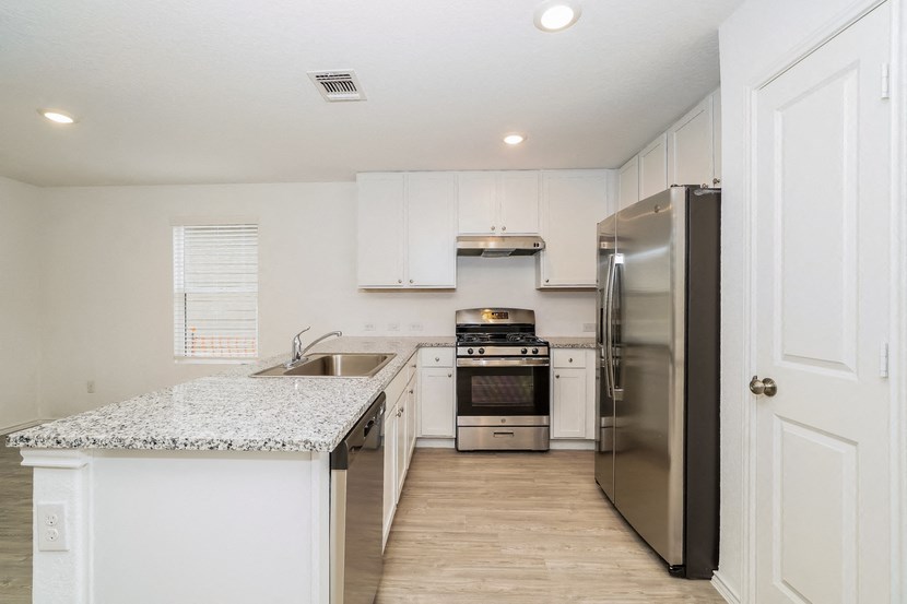 a renovated kitchen with stainless steel appliances and white cabinets