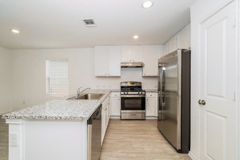 a renovated kitchen with stainless steel appliances and white cabinets