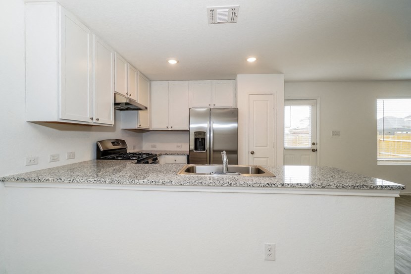 an empty kitchen with white cabinets and a granite counter top