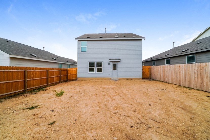 a backyard with a white house and a wooden fence