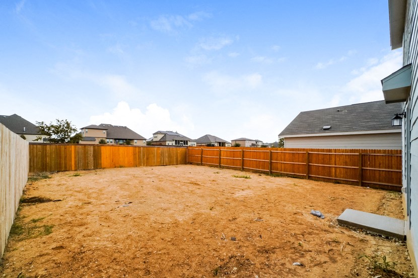 a backyard with a wooden fence and a dirt yard
