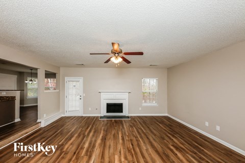 A spacious living room with a fireplace and a ceiling fan.